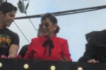 Vilma Santos in a red blouse smiling while on a float at a film promotion